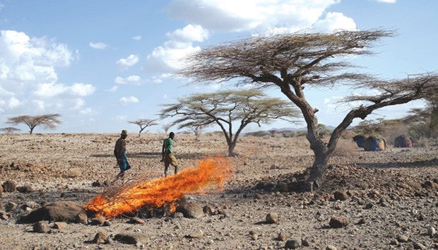 A Turkana tribesman walks past burning goatsu2019 carcasses in a village near Loiyangalani, Kenya.