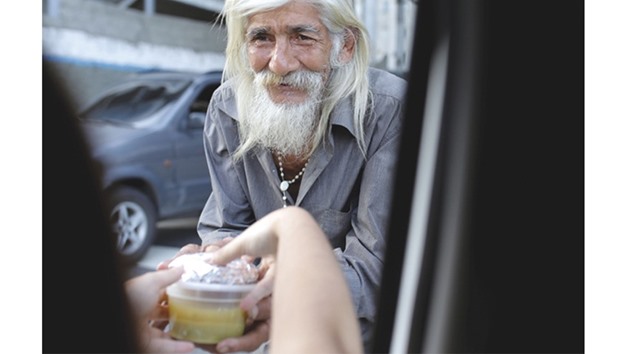 A volunteer of Make The Difference (Haz La Diferencia) charity initiative gives a cup of soup to a homeless man in a street of Caracas.
