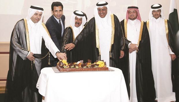 HE the Minister of Justice Dr Hassan Lahdan Saqr al-Mohannadi, HE the Minister of Education and Higher Education Dr Mohamed Abdul Wahed Ali al-Hammadi, and Ministry of Foreign Affairs Secretary General Dr Ahmad Hassan al-Hamadi join Pakistan ambassador Shahzad Ahmad in cutting a cake at the reception as other dignitaries look on.