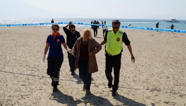 A woman, who survived after a plastic boat carrying Syrians to Greece sank, is helped by a Turkish policeman and medics in the Aegean resort town of Kusadasi, Turkey, on Friday.