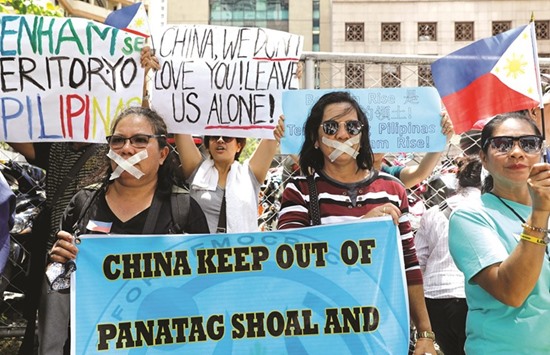 Filipinos hold placards outside the Chinese consulate during a protest over the reports that China would start preparations to build an environmental monitoring station at the disputed South China Sea, in Makati city, Metro Manila yesterday.