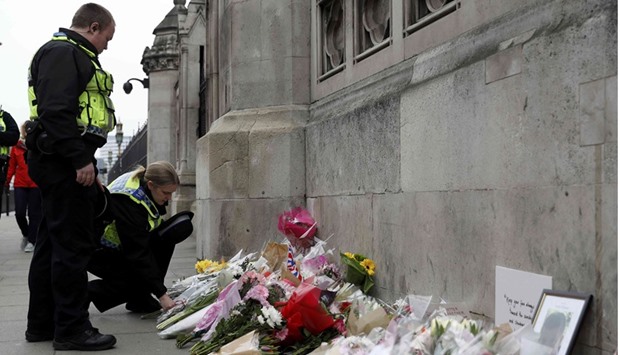 A police officer lays a floral tribute yesterday near Westminster Bridge following the attack in London.