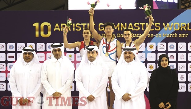 Winners of menu2019s Floor Exercise celebrate on the podium with Qatar Olympic Committee secretary-general Dr. Thani Abdulrahman al-Kuwari yesterday.