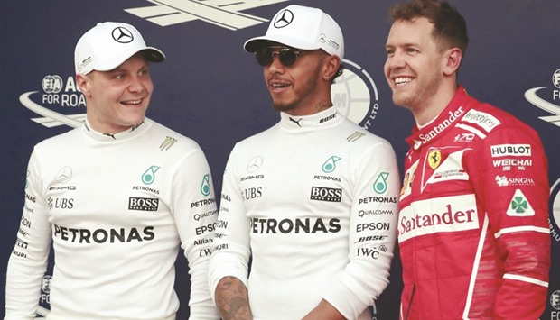 Mercedes driver Lewis Hamilton (C) of Britain reacts after setting pole position in qualifying alongside teammate Valtteri Bottas (L) of Finland and Ferrariu2019s Sebastian Vettel of Germany.