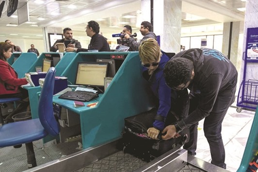 A Tunisian couple bound for London pack away their electronics in their luggage as they check-in for a flight at Tunis-Carthage International Airport yesterday.