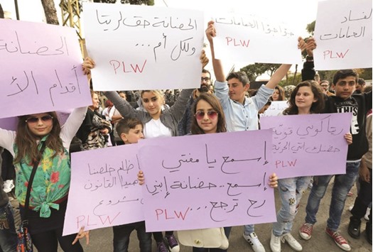 A Lebanese woman holds a placard during a protest seeking the increasing the age at which custody of children for divorced couples can be awarded to the mother, in the capital Beirut. The writing in Arabic reads: u201cRita, you speak on behalf of all of us! The custody of your son is above all.u2019u2019