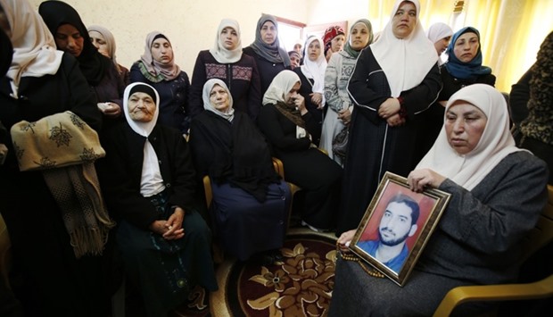 The mother (R) and relatives of Mazen Faqha, who was shot dead by unknown gunmen in the Gaza Strip a day earlier, watch his funeral on tv at their home in the West Bank village of Tubas.