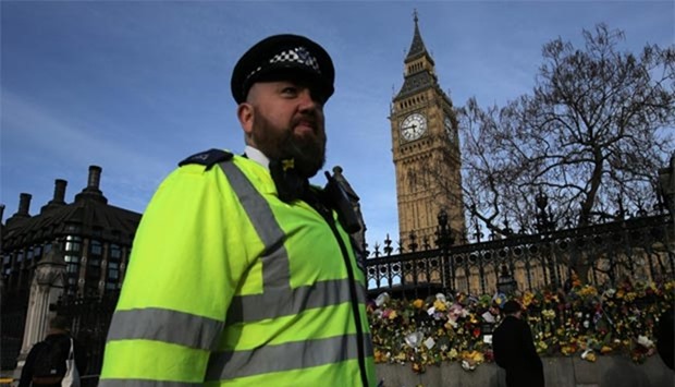 A policeman walks past floral tributes to the victims of the March 22 terror attack in front of the Elizabeth Tower, more commonly referred to as Big Ben, in London on Sunday.