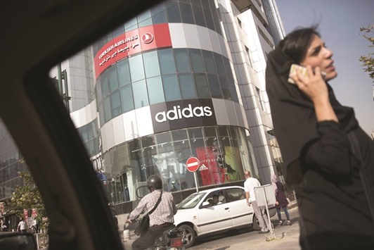 A pedestrian using a smartphone passes an Adidas sports goods store in Tehran on August 25, 2015. Optimism among the estimated 1mn Americans of Iranian  descent has dimmed given US President Donald Trumpu2019s labelling of Iranu2019s 2015 nuclear deal with world powers as a u201cdisasteru201d and his vow to deal aggressively with the Islamic Republic.