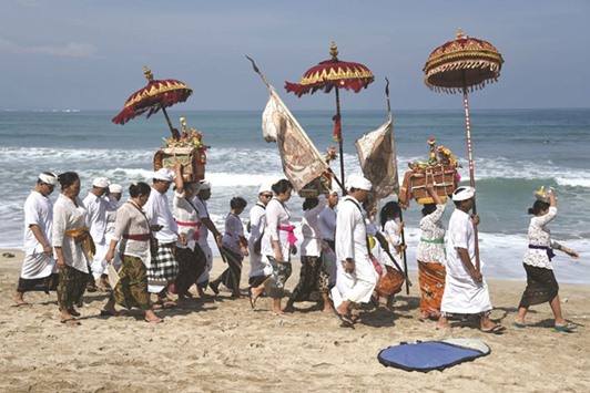 Balinese people walk along Kuta beach to attend prayers for the Melasti ceremony near Denpasar on the Indonesian resort island of Bali on Saturday. The Melasti is a purification festival held u2018Nyepiu2019, a day of silence, when Hindus on the island of Bali are not allowed to work, travel or take part in any indulgence. The Indonesian holiday island of Bali shuts down for the day of silence to mark the Hindu new year.