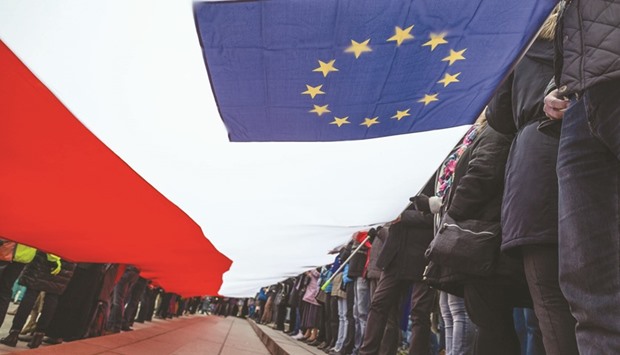 People hold a giant Polish and EU flag during a demonstration of the Committee for Democracy Defence (KOD), in Warsaw, on March 25, to mark the 60th anniversary of the Rome treaty.