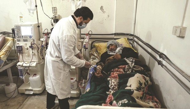 Kidney specialist Mohamed Sadeq, a 34-year-old Syrian physician, attends to his patient, who suffers from renal insufficiency, as he undergoes treatment in the basement-turned-clinic in the rebel-held town of Douma.
