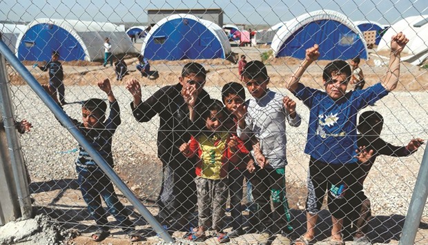 Displaced Iraqi children, who fled the violence in the northern city of Mosul as a result of a planned operation to retake the city from militants, stand behind a fence at the Hasan Sham camp yesterday.