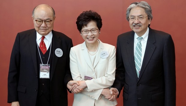 Carrie Lam (C) poses with Woo Kwok-Hing (L) and John Tsang (R) as they greet election committee members.