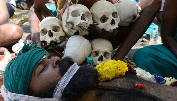An Indian farmer from the southern state of Tamil Nadu plays dead near symbolic ,skulls, as he takes part in a protest in New Delhi