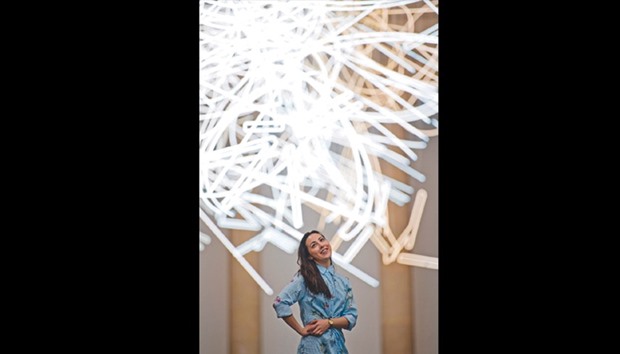 A gallery assistant poses for photographers during a photocall to promote Welsh artistu2019s Cerith Wyn Evans new light installation entitled u2018Forms in Space... by Light (in Time)u2019, made up of nearly 2km of neon lights, at Tate Britain in London yesterday.