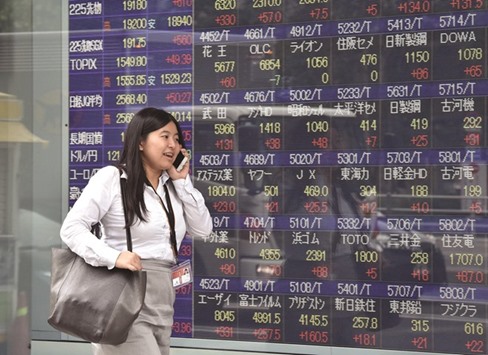 A woman passes before a share prices board in Tokyo. The Nikkei 225 closed up 1.1% to 19,202.87 points yesterday.