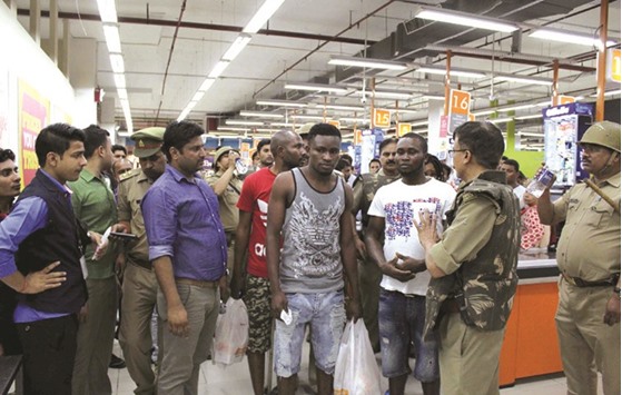 Police and onlookers surround African nationals at a shopping mall in Greater Noida late Monday.