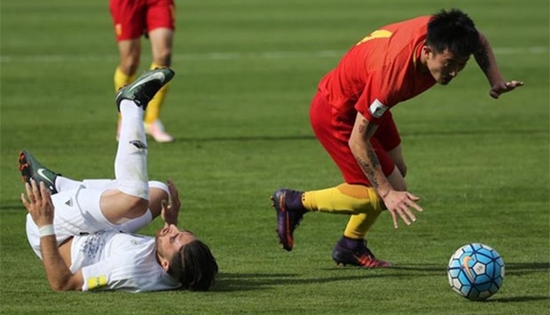 Iran's Alireza Jahanbakhsh falls as he fights for the ball with China's Jiang Zhipeng during a World Cup qualifying match in Tehran on Tuesday.