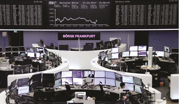 Traders work at their desks in front of the German share price index, DAX, at the stock exchange in Frankfurt. European stock markets posted modest gains yesterday as Britain triggered the two-year process to quit the European Union, investors already having largely priced in u201cBrexitu201d since last yearu2019s referendum.