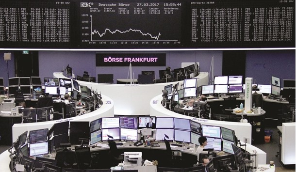Traders work at their desks in front of the German share price index, DAX, at the stock exchange in Frankfurt. European stock markets posted modest gains yesterday as Britain triggered the two-year process to quit the European Union, investors already having largely priced in u201cBrexitu201d since last yearu2019s referendum.