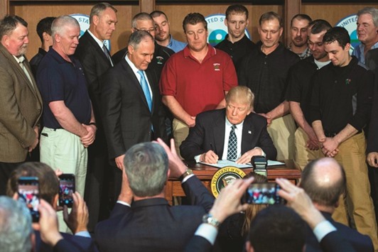 Surrounded by miners from Rosebud Mining, President Donald Trump signs the Energy Independence Executive Order at the Environmental Protection Agency Headquarters in Washington. President Donald Trump claimed an end to the u201cwar on coalu201d Tuesday, as he moved to roll back climate protections enacted by predecessor Barack Obama.