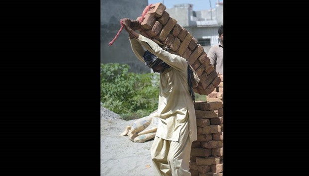 A Pakistani labourer carries bricks on his back at a construction site at a residential area in Islamabad yesterday.