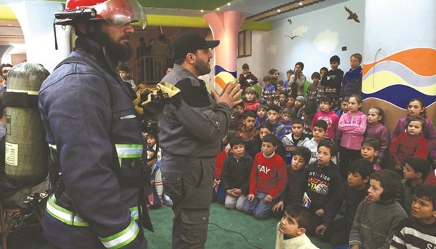 A Civil Defence member stands among children during a war safety awareness campaign in the rebel held besieged city of Douma, in the eastern Damascus suburb of Ghouta, Syria, yesterday.