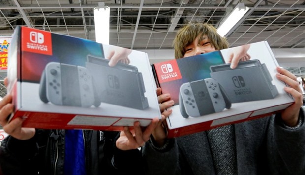 Customers pose with their Nintendo Switch game consoles