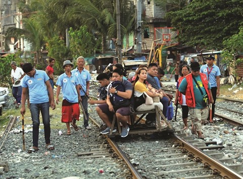 Members of the Filipino community (barangay) local security forces, which  according to the group conducts foot patrol to deter crime and drug abuse in their neighbourhood, carry batons while walking past commuters at a railroad track in Santa Mesa, Metro Manila, yesterday.