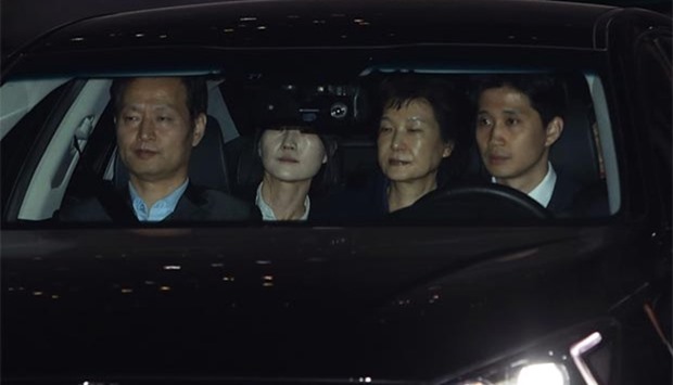 Park Geun-hye (second right) leaves the prosecutors' office in a car as she is transferred to a detention house early on Friday.