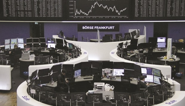 Traders work at their desks in front of the DAX board at the Frankfurt Stock Exchange. The DAX 30 closed down 0.3% at 12,027.36 points yesterday.