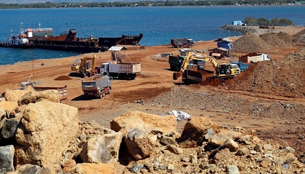 Trucks load rocks containing nickel-ore minerals into a barge in Philippines