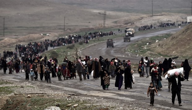 Iraqi families walk down a road as they flee Mosul