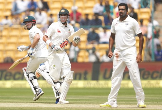 Australiau2019s Matt Renshaw and Shaun Marsh (centre) run between the wickets as Indian spinner Ravichandran Ashwin (right), looks on during the second day's play of second Test in Bangalore yesterday. (Reuters)