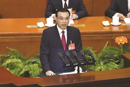 Chinese Premier Li Keqiang delivers his report during the opening session of the National Peopleu2019s Congress in Beijingu2019s Great Hall of the People yesterday. China has cut its growth target this year as the worldu2019s second-largest economy pushes through painful reforms to address a rapid build-up in debt, and erects a u201cfirewallu201d against financial risks.
