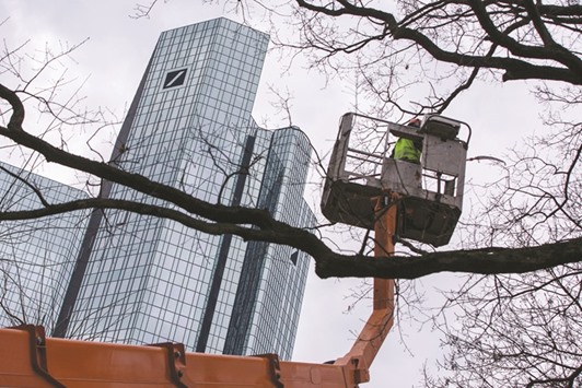 A worker stands in a cherry picker as the twin tower skyscraper headquarters of Deutsche Bank stand beyond in Frankfurt. In a statement yesterday, Deutsche Bank said it will keep its Postbank consumer division and cut total costs to u20ac22bn by 2018.