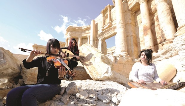 Syrian musicians play their instruments while resting on damage in the amphitheatre of the historic city of Palmyra.