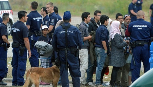Asylum-seekers waiting to board a bus at their temporary Hungarian home of Roszke border village at the Hungarian-Serbian border to transport them to a new refugee camp on June 25, 2015 after a conflict between migrants.