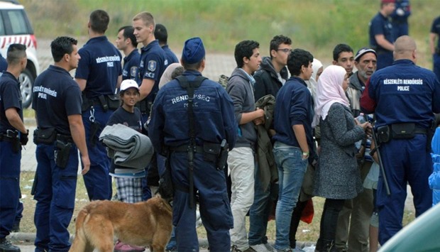 asylum-seekers waiting to board a bus at their temporary Hungarian home