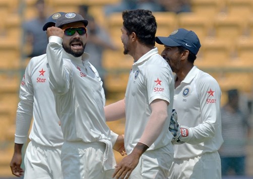 This file photograph taken on March 7, 2017, shows Indian captain Virat Kohli (L) celebrates with bowler Umesh Yadav (C) and other teammates after the dismissal of Australian captain Steve Smith during the fourth day of the second Test in Bangalore. (AFP)