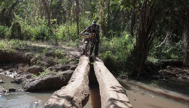 Joseph crosses a bridge to reach his field near Obo, Central African Republic.