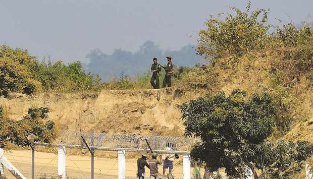 Myanmar army personnel keeping watch as Myanmar workers build a fence along the Myanmar-Bangladesh border, as seen from Tombru in the Bangladeshi district of Bandarban yesterday.