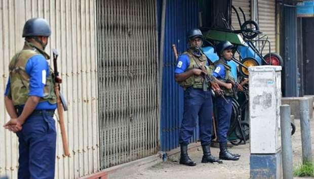 Sri Lankan soldiers stand guard near shops in Colombo on Friday following communal violence in other parts of the country.