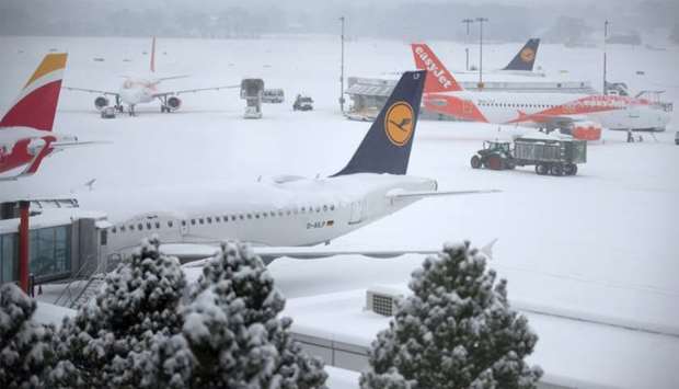 A tractor removes snow next to EasyJet and Lufthansa aircrafts during a temporary closure at Cointrin airport in Geneva