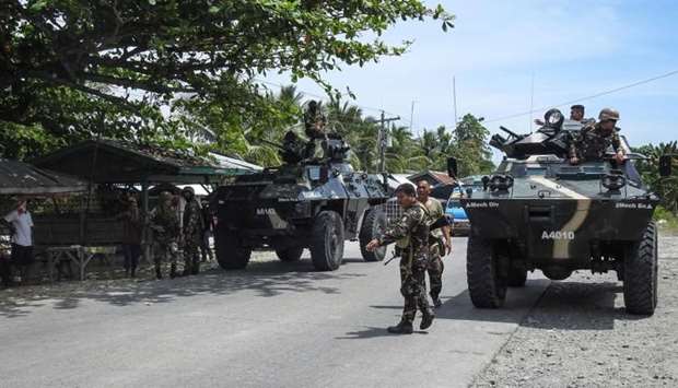 Philippine soldiers standing next to their armoured personnel carriers as they man a checkpoint along a highway near the clash site