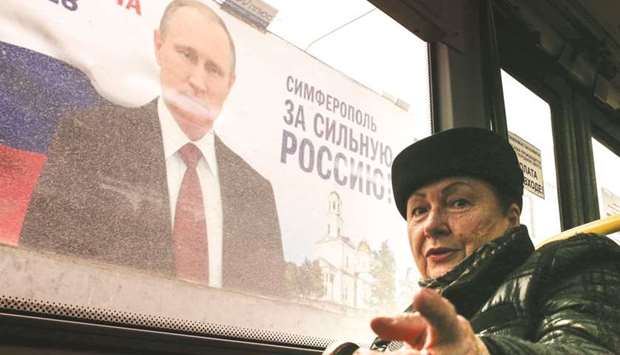 A commuter sits in a bus passing in front of a campaign billboard of Putin, reading u2018Simferopol for a Strong Russia!u2019 in Simferopol, Crimea. Russia will vote for president on March 18.