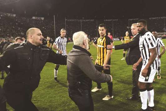 Paok Thessaloniki president Ivan Savvidis (centre) carrying a handgun in his waistband to the pitch after the referee refused a last minute goal during the Greek Superleague match between Paok Thessaloniki and AEK Athens in Thessaloniki on Sunday. (AFP)