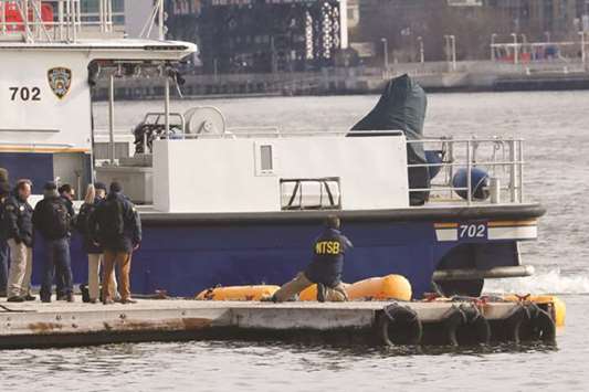 National Transportation Safety Board investigators look at the scene of the wreckage of a chartered Liberty Helicopters chopper that crashed into the East River late on Sunday.
