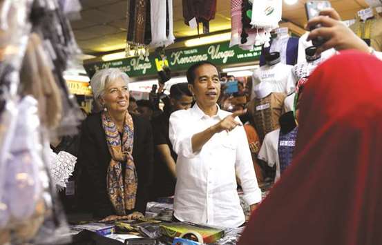 International Monetary Fund managing director Christine Lagarde (left) and Indonesian President Joko Widodo visit the Tanah Abang market in Jakarta. Lagarde said yesterday that tax cuts can lift the US growth rate by about 1.2 percentage points over the three years through 2020, which should help boost global growth and trade for at least a few years.